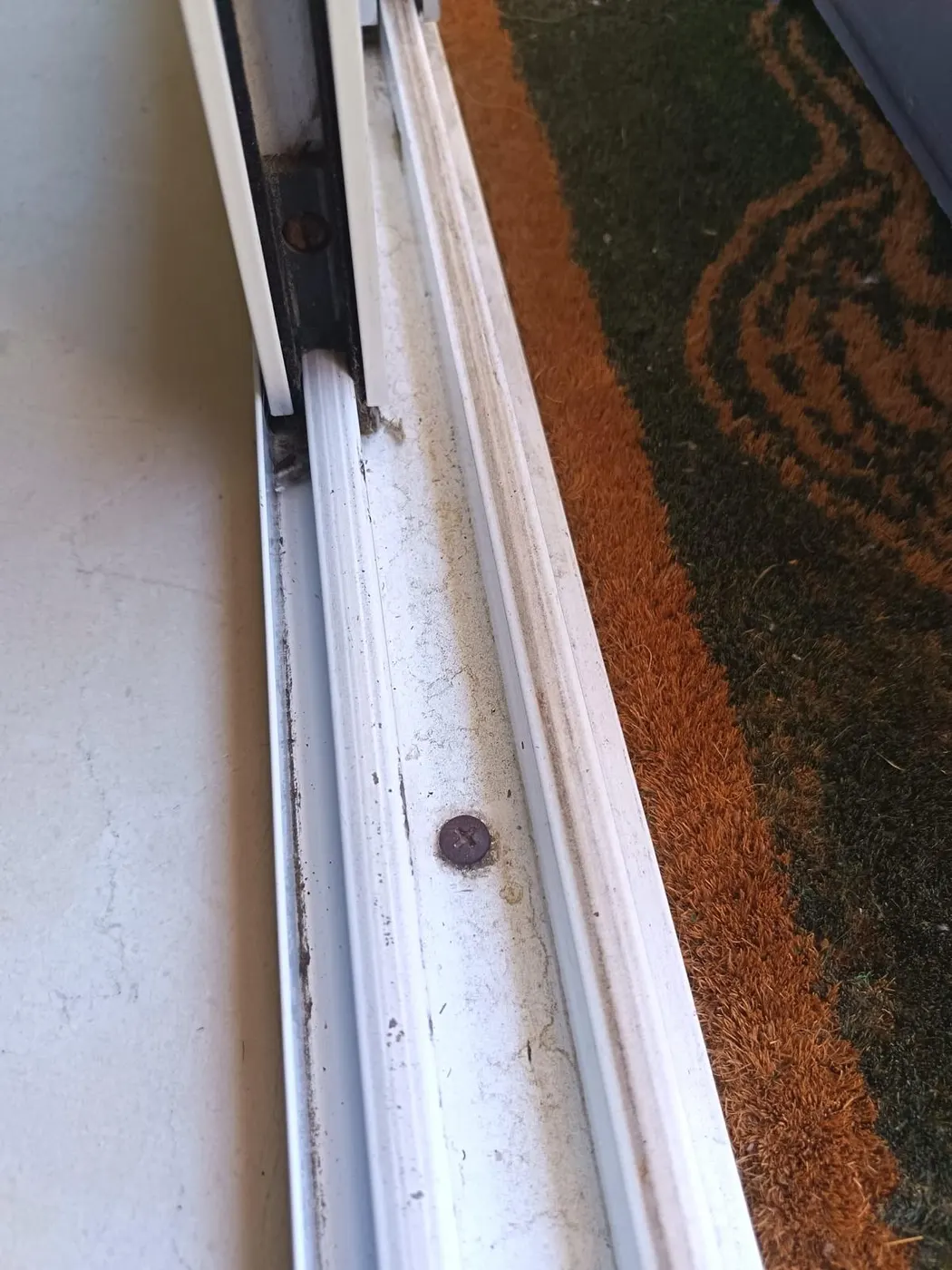 Rail de puerta corredera con suciedad y restos de obra incrustados antes de la limpieza